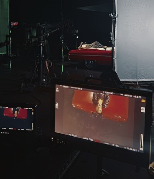 alt="Акторка лежить на капоті ретро кабріолета — кадр з монітору під час зйомки кліпу Dannisha KISS