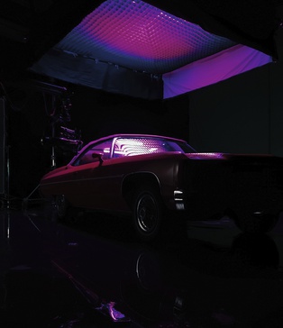 Червоний кабріолет під фіолетовим світлом — постановка зйомки кліпу KISS у темному павільйоні