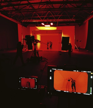 Backstage зйомки кліпу KISS — акторка у неонових штанах позує перед світловим кубом