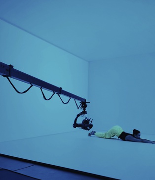 кторка у неонових штанах тягнеться вперед у синьому світлі — сцена з кліпу KISS у павільйоні SP Studio